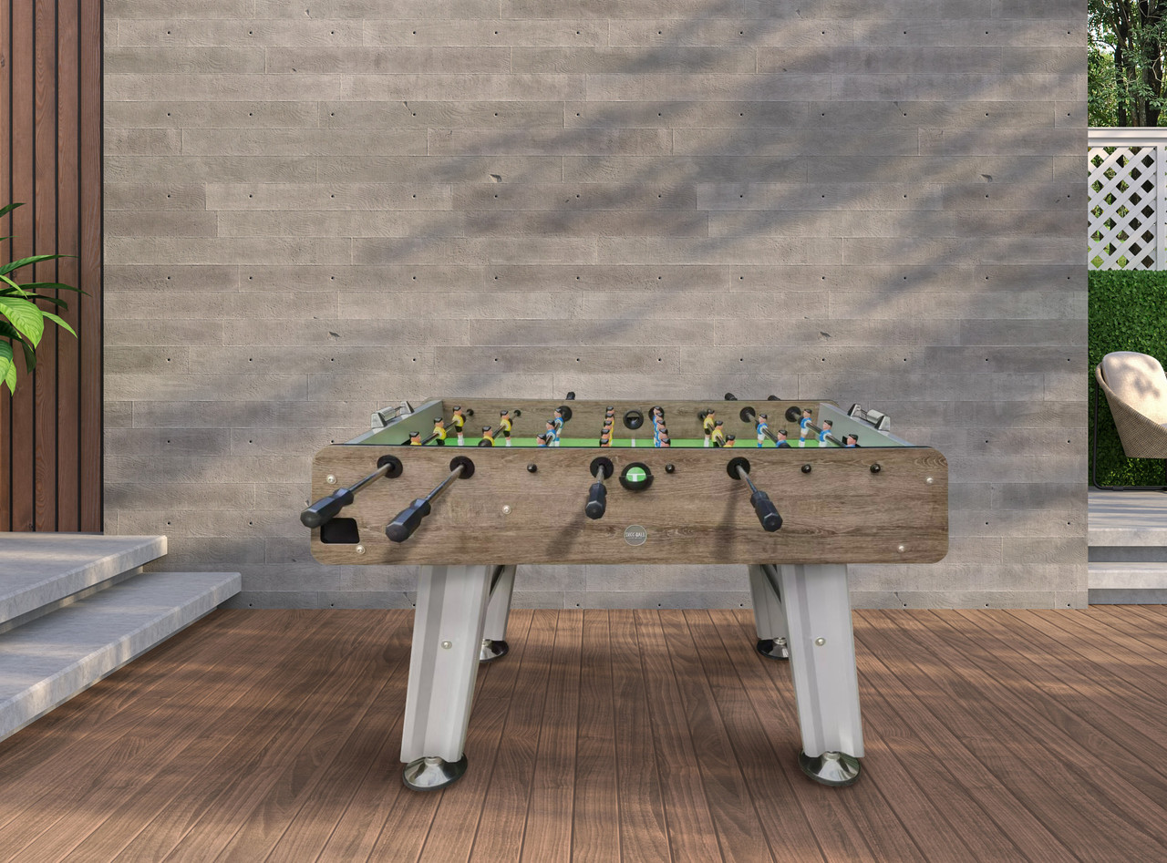 Foosball table outdoors against a wooden wall