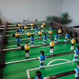 Foosball table with players in blue and yellow uniforms on a green playing surface.