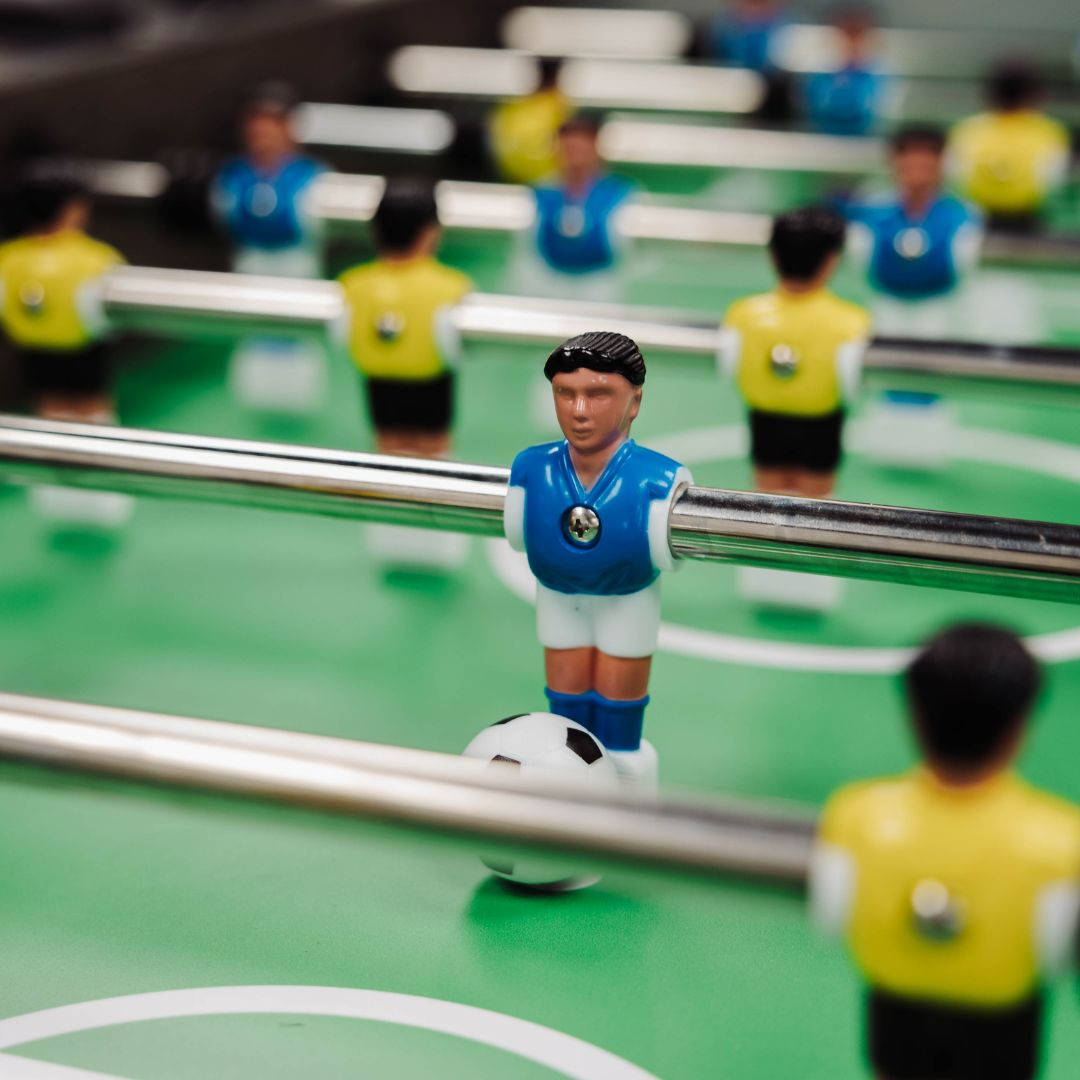 Table football set with players in blue and yellow uniforms on a green playing field.